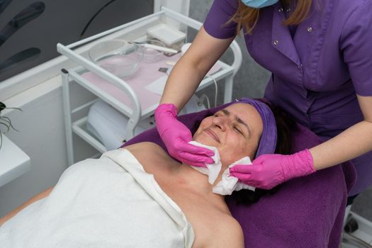 The beautician gently rubs the exfoliating preparation all over the skin of the face