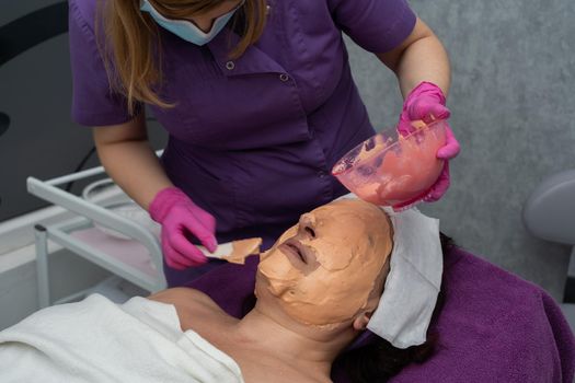 A professional algae mask is applied to the client's face with a spatula