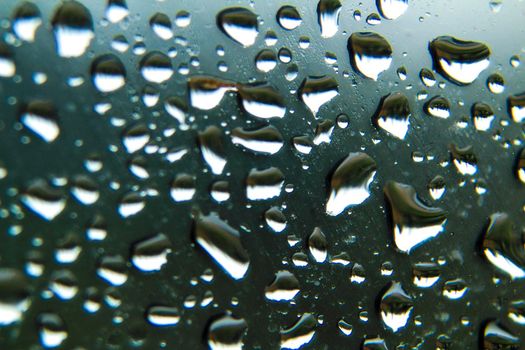 Raindrops on window pane on a cold and cloudy day of winter