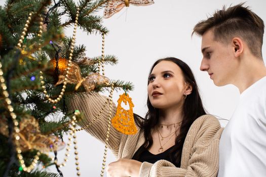 Couple in love while decorating the Christmas tree for Christmas. Smiling young people.