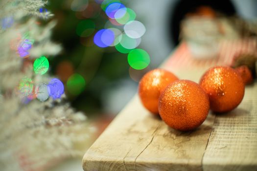 Decoration on the fireplace for Christmas. Shimmering Christmas balls in gold. Christmas tree lights in the background.