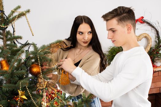 Couple in love while decorating the Christmas tree for Christmas. Smiling young people.