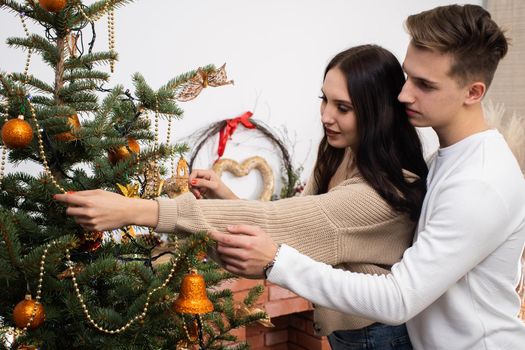 Couple in love while decorating the Christmas tree for Christmas. Smiling young people.