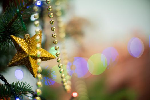 Festive decoration for choice. Gold Christmas tree star. Christmas tree lights in the background. Christmas decorations.