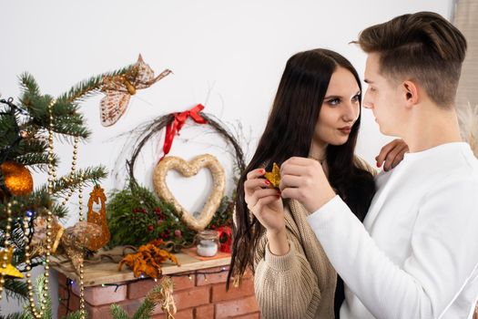 The bride and groom will continue to decorate the Christmas tree. Decoration of a Christmas tree for Christmas in December.