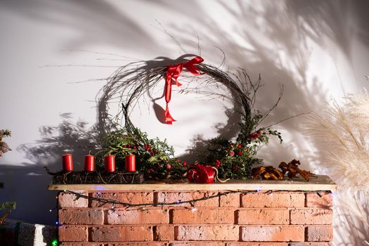 On a decorative red brick fireplace are four red candles as decoration for Christmas.