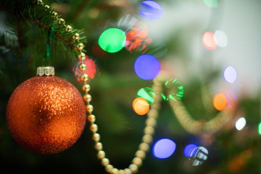 A shiny ornament in the shape of a round Christmas ball attached to a Christmas tree on a Christmas background with cork lights.