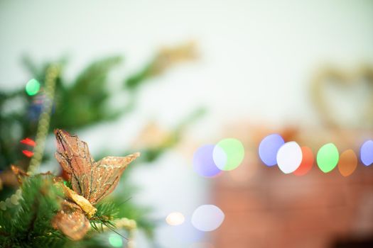 Festive decoration for choice. Golden decorative butterfly on the Christmas tree. Christmas tree lights in the background. Christmas decorations.