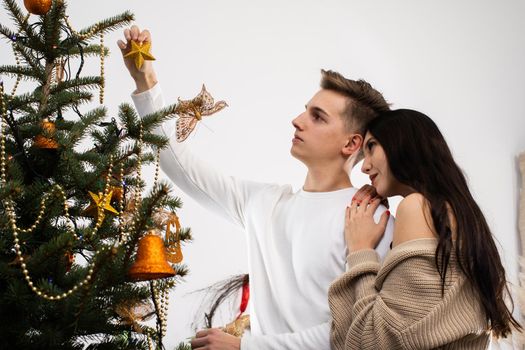 The bride and groom will continue to decorate the Christmas tree. Decoration of a Christmas tree for Christmas in December.