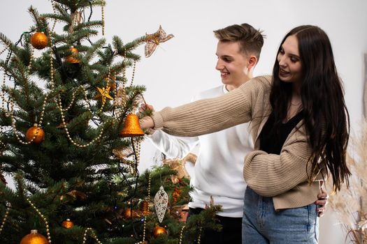 Couple in love while decorating the Christmas tree for Christmas. Smiling young people.