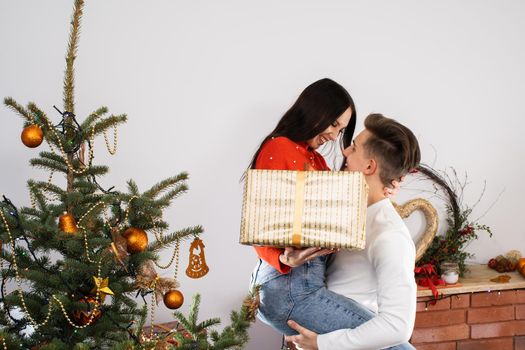 The fiance lifted his partner up in a fit of joy. Lovers flirt in a decorated living room at home. December Christian holidays.