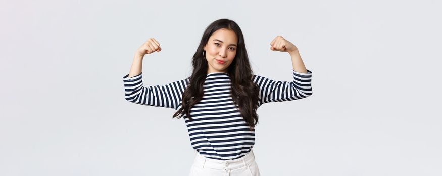 Lifestyle, people emotions and casual concept. Strong and confident asian woman flex biceps, bragging her perfect shape after sign-up gym membership, brag with muscles, workout and feeling strong.