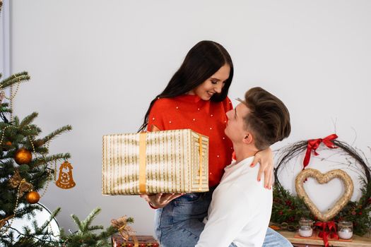 The fiance lifted his partner up in a fit of joy. Lovers flirt in a decorated living room at home. December Christian holidays.