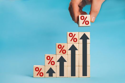 Wooden blocks with percentage sign and arrow up, financial growth, interest rate increase, inflation concept. Concept of interest financial and mortgage rates.