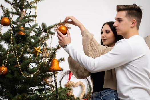 Couple in love while decorating the Christmas tree for Christmas. Smiling young people.