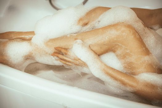 Women's feet in bath foam. View from above. Enjoy and relax in a spa hotel.