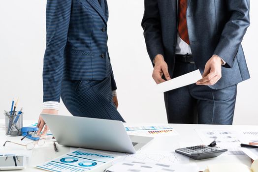 Business consultation and discussing with colleagues in office. Corporate teamwork and collaboration. Professional analysis of financial indexes. Businessman and businesswoman stand near desk