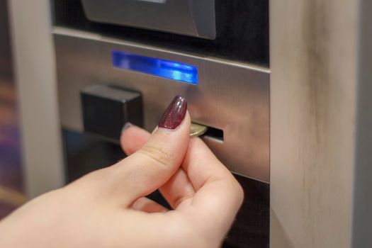 human hand inserting a coin in a vending machine. Close-up 