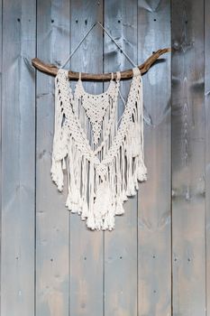 Handmade stylish cotton macrame decoration hanging on a white empty wall. Copy space.