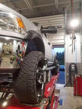 Closeup of tire clamped with aligner undergoing auto wheel alignment