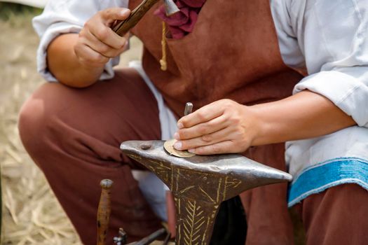 Close up image of the artist at work. He is carefully using a hammer made a decoration