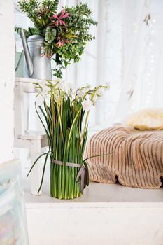 Stylish and modern boho interior of living room with flowers in vase, beige macrame and elegant accessories