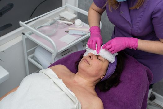 The beautician gently rubs the exfoliating preparation all over the skin of the face