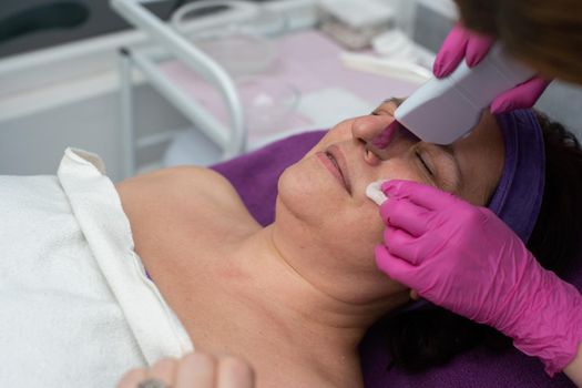 Cavitation device. The beautician gently guides the ultrasound device over the client's face to exfoliate the epidermis.