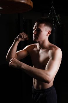 The athlete blows practices the bag boxer glove black young male competition, In the afternoon muscular fighter from power and fit guy, sportswear sweat. Person model dark, sexy