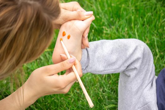 child sitting on the grass, smiling on the child's leg with paints