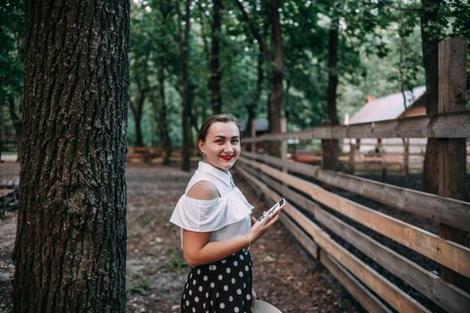 photo of a smiling blonde in the forest with a phone, who is going to take a photo, a beautiful summer forest