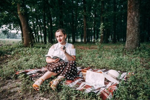 a girl with glasses reads a book in a summer forest