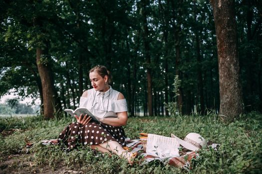 a girl with glasses reads a book in a summer forest