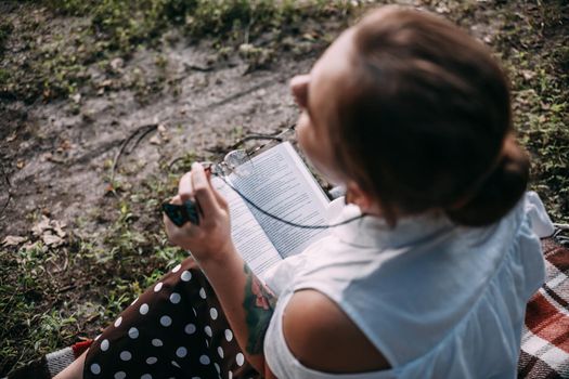 a girl with glasses reads a book in a summer forest
