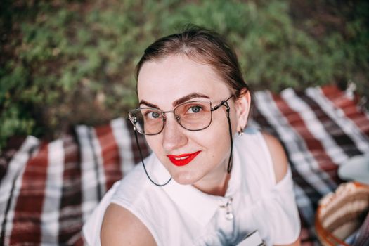 a girl with glasses reads a book in a summer forest