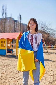 Portrait of a joyful Ukrainian woman holding a child and a Ukrainian flag. The girl is waiting for her husband from the war. War between Russia and Ukraine