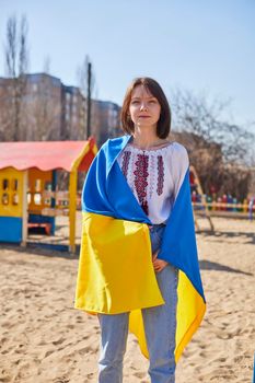 Portrait of a joyful Ukrainian woman holding a child and a Ukrainian flag. The girl is waiting for her husband from the war. War between Russia and Ukraine