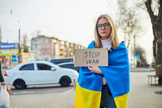 Portrait of a joyful Ukrainian woman holding a Ukrainian flag and a sign. The girl is waiting for her husband from the war. War between Russia and Ukraine