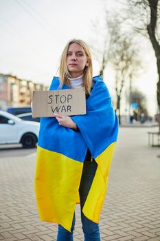 Portrait of a joyful Ukrainian woman holding a Ukrainian flag and a sign. The girl is waiting for her husband from the war. War between Russia and Ukraine