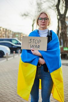 Portrait of a joyful Ukrainian woman holding a Ukrainian flag and a sign. The girl is waiting for her husband from the war. War between Russia and Ukraine