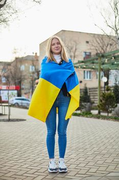 Portrait of a joyful Ukrainian woman holding a Ukrainian flag and a sign. The girl is waiting for her husband from the war. War between Russia and Ukraine