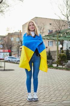 Portrait of a joyful Ukrainian woman holding a Ukrainian flag and a sign. The girl is waiting for her husband from the war. War between Russia and Ukraine