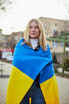 Portrait of a joyful Ukrainian woman holding a Ukrainian flag and a sign. The girl is waiting for her husband from the war. War between Russia and Ukraine