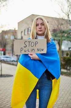 Portrait of a joyful Ukrainian woman holding a Ukrainian flag and a sign. The girl is waiting for her husband from the war. War between Russia and Ukraine