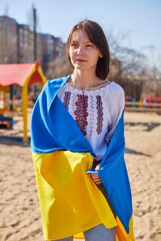 Portrait of a joyful Ukrainian woman holding a child and a Ukrainian flag. The girl is waiting for her husband from the war. War between Russia and Ukraine