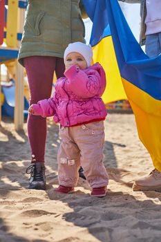 Portrait of a joyful Ukrainian woman holding a child and a Ukrainian flag. The girl is waiting for her husband from the war. War between Russia and Ukraine