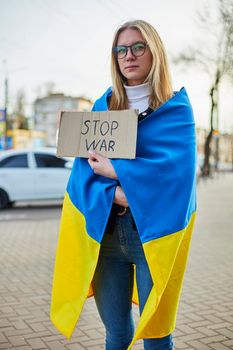 Portrait of a joyful Ukrainian woman holding a Ukrainian flag and a sign. The girl is waiting for her husband from the war. War between Russia and Ukraine