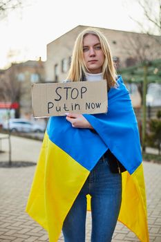 Portrait of a joyful Ukrainian woman holding a Ukrainian flag and a sign. The girl is waiting for her husband from the war. War between Russia and Ukraine