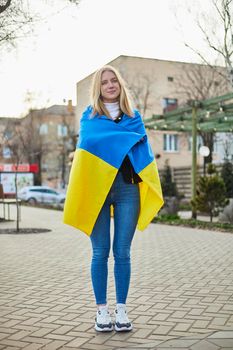 Portrait of a joyful Ukrainian woman holding a Ukrainian flag and a sign. The girl is waiting for her husband from the war. War between Russia and Ukraine