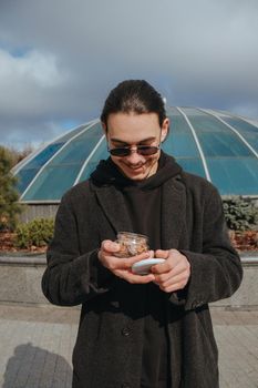 Young gay hipster eating peanuts at the street smiling happy sunglasses. Healthy lifestyle